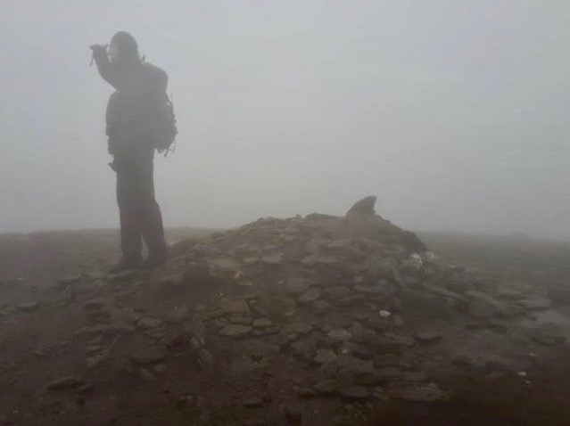 The barely visible summit cairn of Meall Corranaich in heavy rain